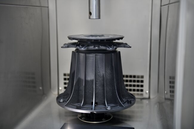 Plot réglable robuste soumis à des tests de charge pour dalles de terrasse.