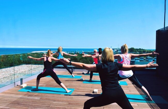 Terrasse sur toit construite avec des plots réglables accueillant un cours de yoga en plein air.