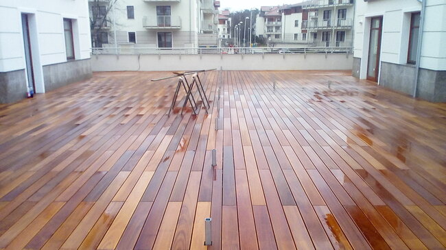 terrasse en bois poli dans la cour d'un complexe d'appartements avec des planches mouillées et des chevalets de construction.