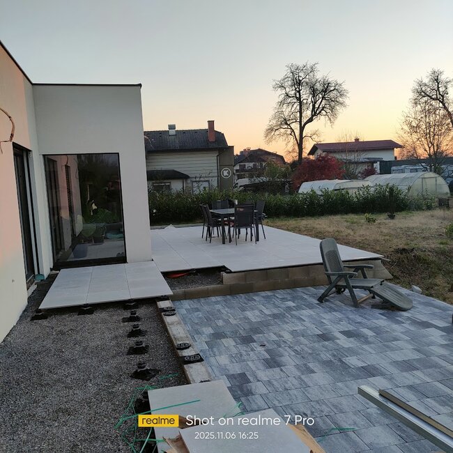 Installation moderne de patio montrant des dalles de terrasse surélevées montées sur des plots réglables à côté d'une section pavée.
