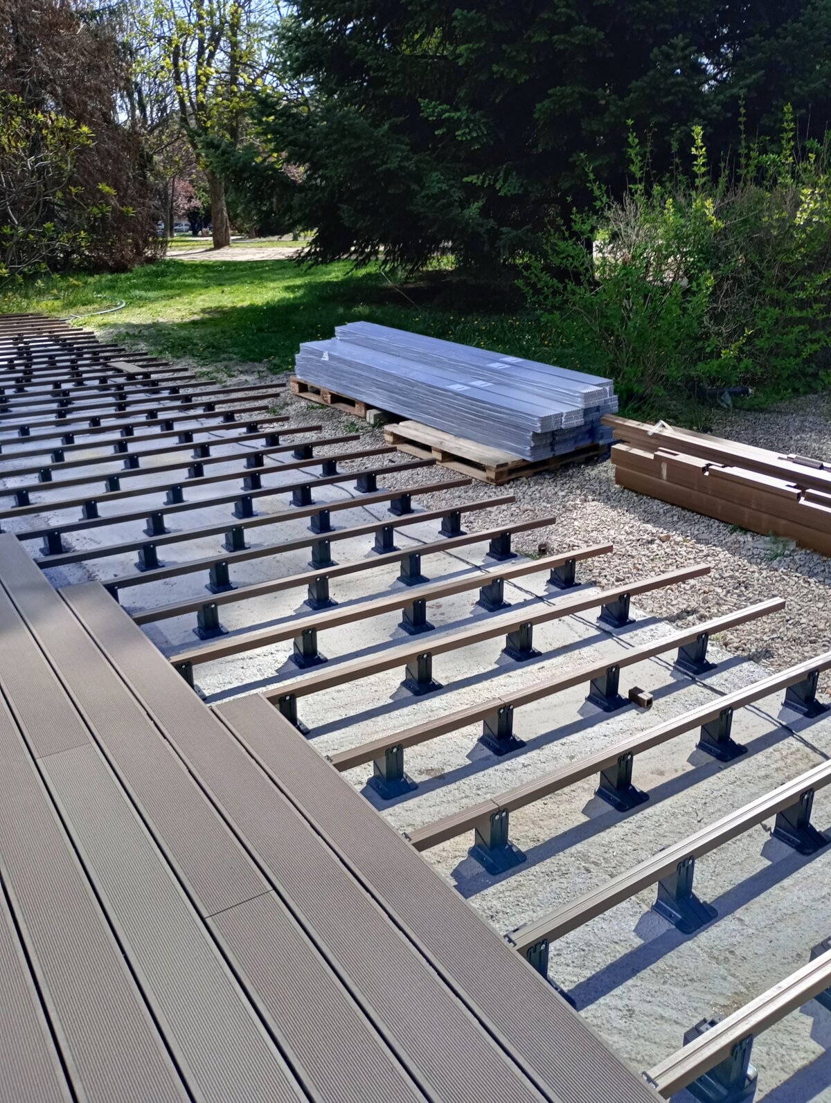 Lames de terrasse composites installées sur des lambourdes en aluminium soutenues par des plots réglables.