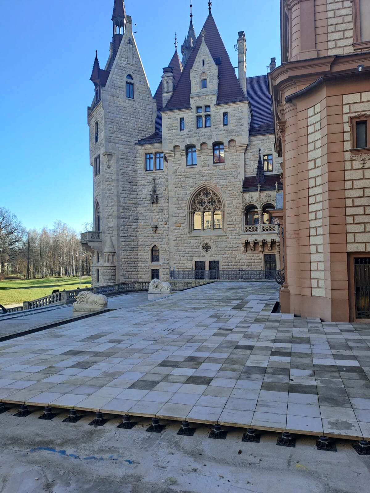 Terrasse surélevée en dalles de pierre installée sur des plots réglables de terrasse devant un bâtiment historique.