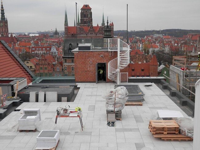 Terrasse sur toit en cours de construction avec une surface surélevée en dalles de terrasse sur plots réglables.