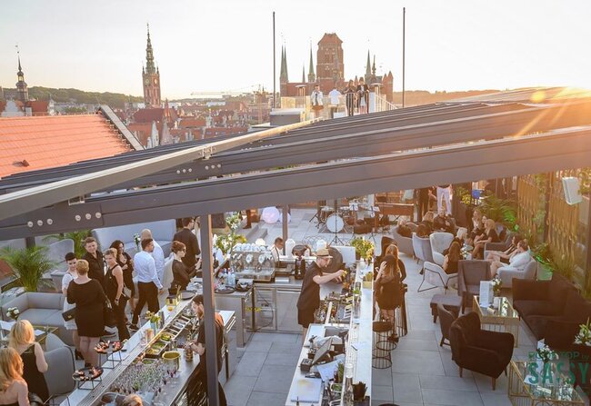 Terrasse commerciale sur toit construite sur un système de plots réglables pour terrasse lors d'un événement au coucher du soleil.