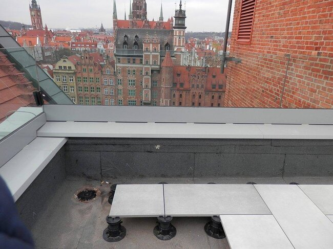 Installation de dalles de terrasse surélevées soutenues par des plots réglables en plastique pour terrasse sur une terrasse sur toit.
