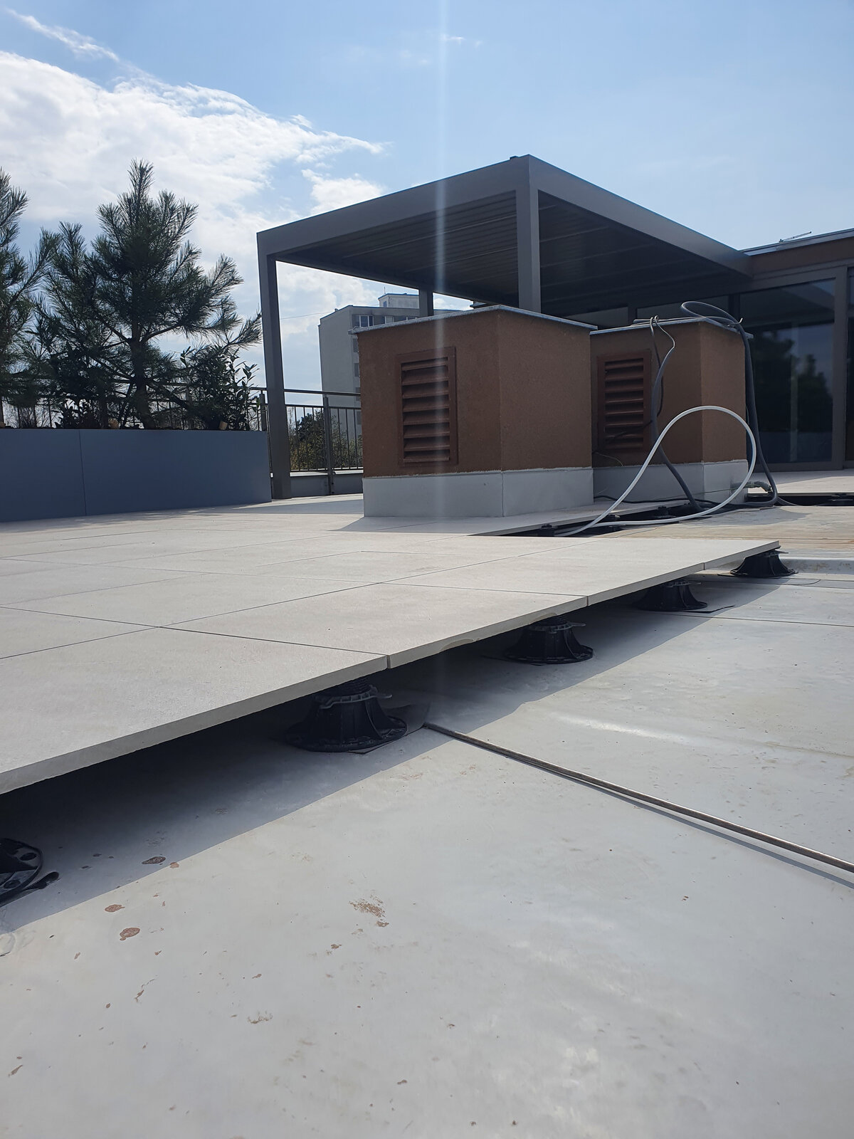 Système de plots réglables supportant des dalles de terrasse surélevées à l'extérieur.