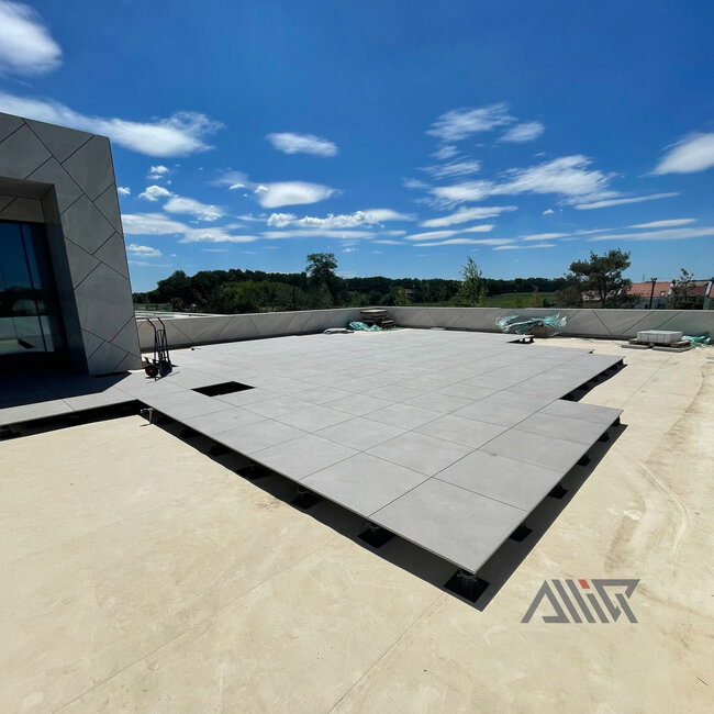 Système de plancher surélevé avec dalles supporté par des plots réglables noirs de terrasse.