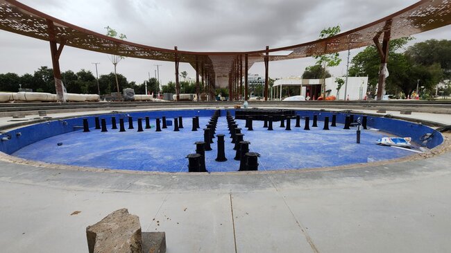 Plots réglables installés sur un bassin de fontaine carrelé de bleu dans un système de terrasse surélevée pour installation hydraulique extérieure.