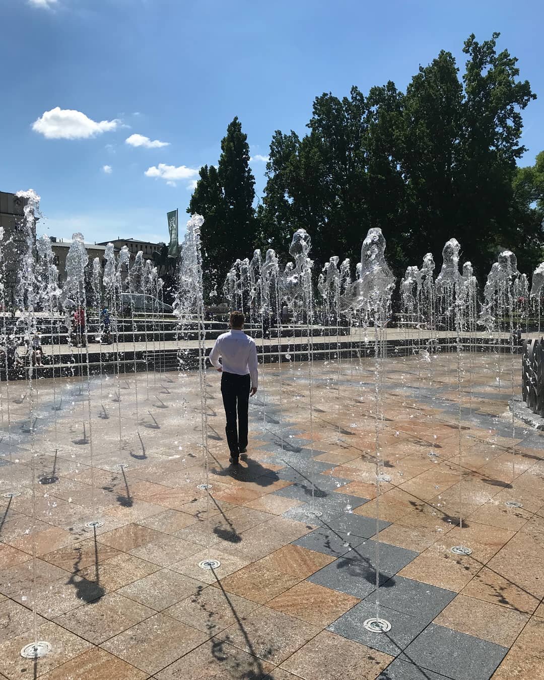 Fontaine extérieure à dalle sèche terminée avec buses intégrées installée sur un système de dalles surélevées à plots réglables.