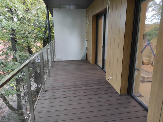 Terrasse composite finie installée sur un balcon moderne à l'aide de plots réglables.
