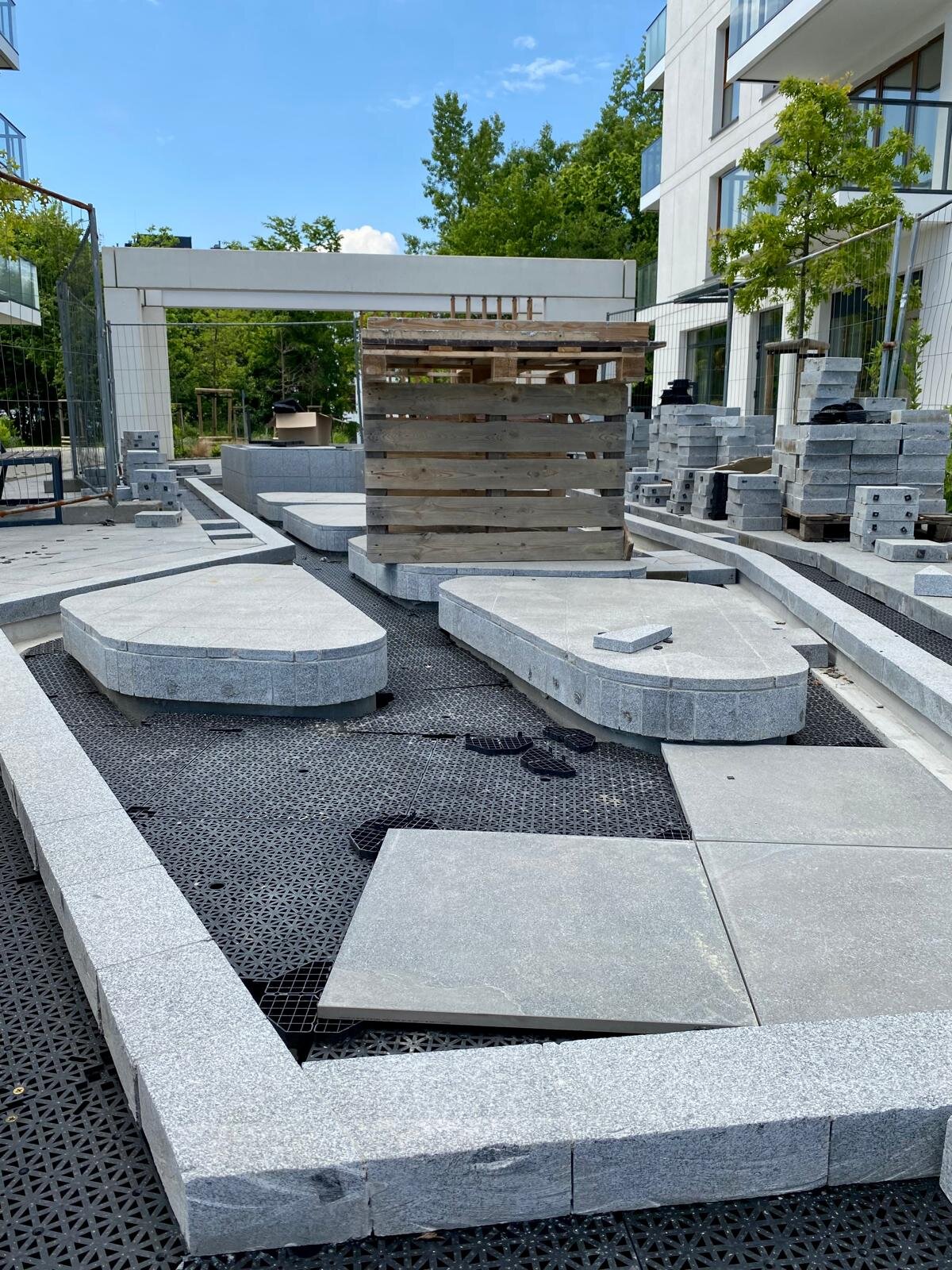 Panneaux de sous-plancher drainants à emboîtement DeckSafe en cours d'installation sous des dalles de pierre sur un projet de terrasse extérieure.